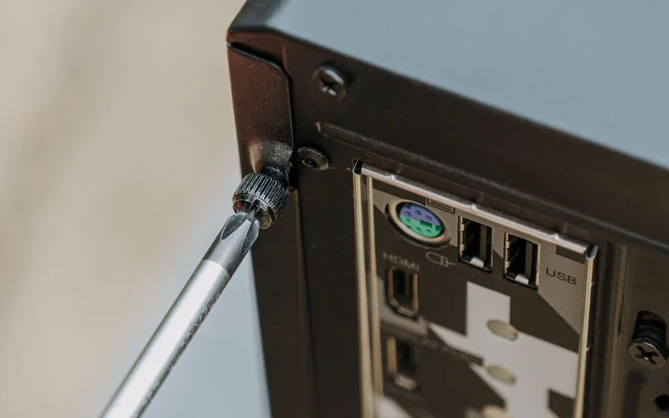 Schroevendraaier aan de vleugelschroef van een opengeschroefde computerkast