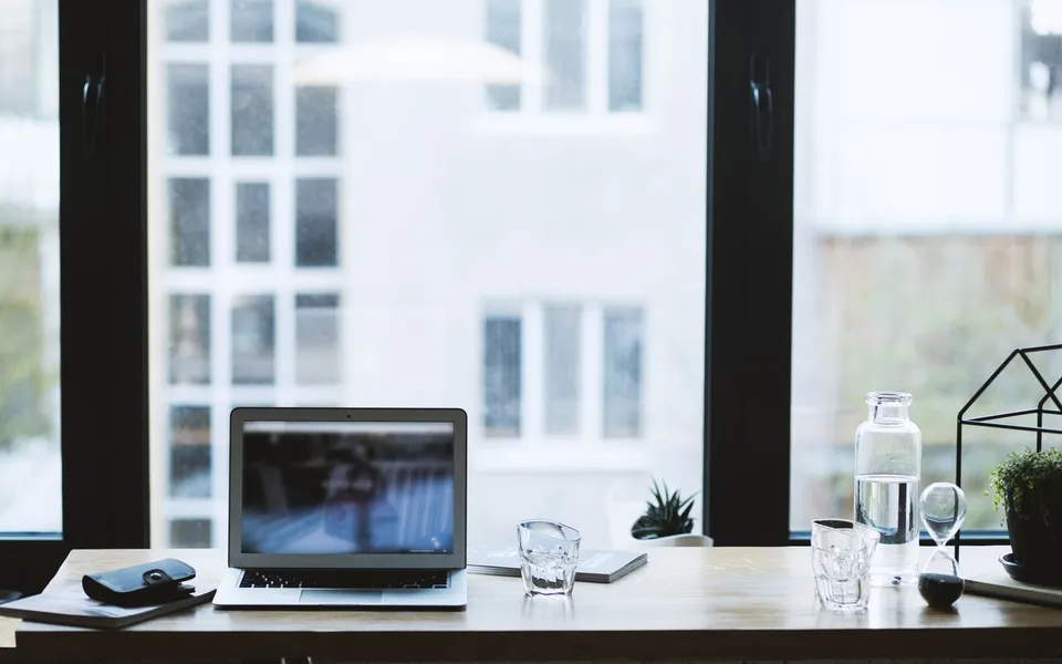 Laptop op een houten tafel bij het raam